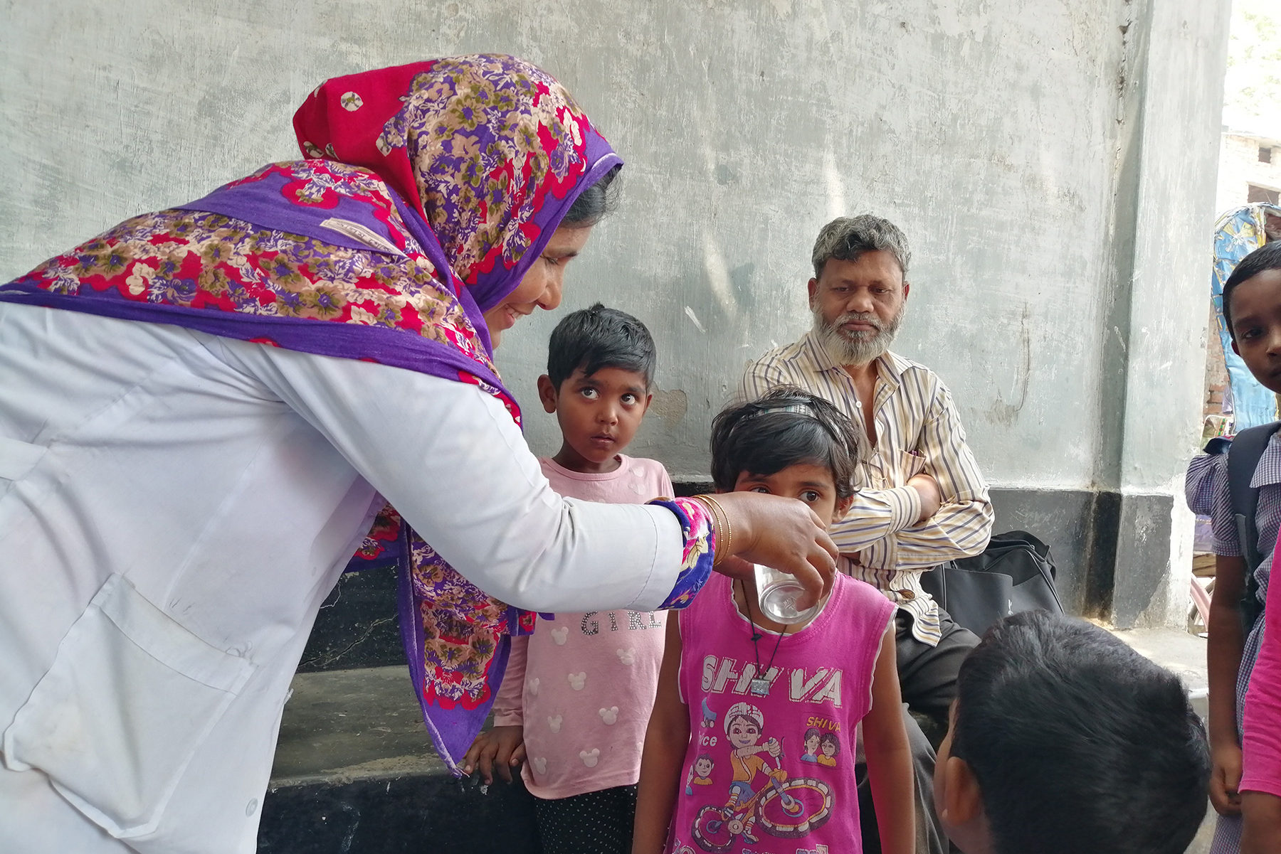 A community health worker treats a child with deworming medication