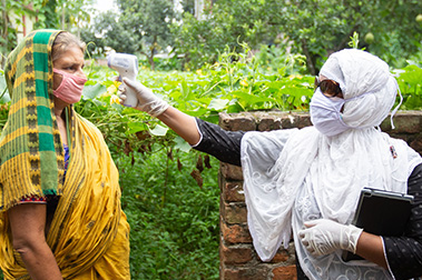 A BRAC community health worker checks a patient's temperature