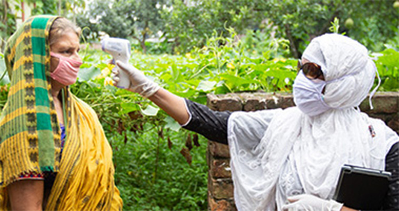 A BRAC community health worker checks a patient's temperature